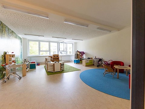 Ein Raum mit Rollenspiel-Ausstattungen wie bunten Kostümen, Einkaufswagen und Puppenwagen.