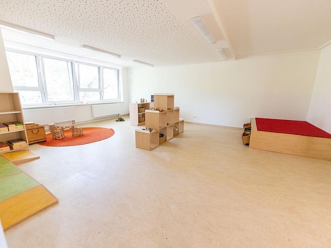 Ein Bauraum mit viel freiem Platz in der Mitte; im hinteren Bereich ist eine gut ausgestattete Bauecke mit verschiedenen Baumaterialien.